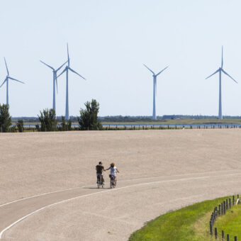 Windmolens en een zeedijk waar fietsers fietsen