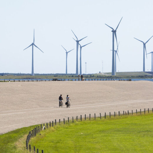 Windmolens en een zeedijk waar fietsers fietsen