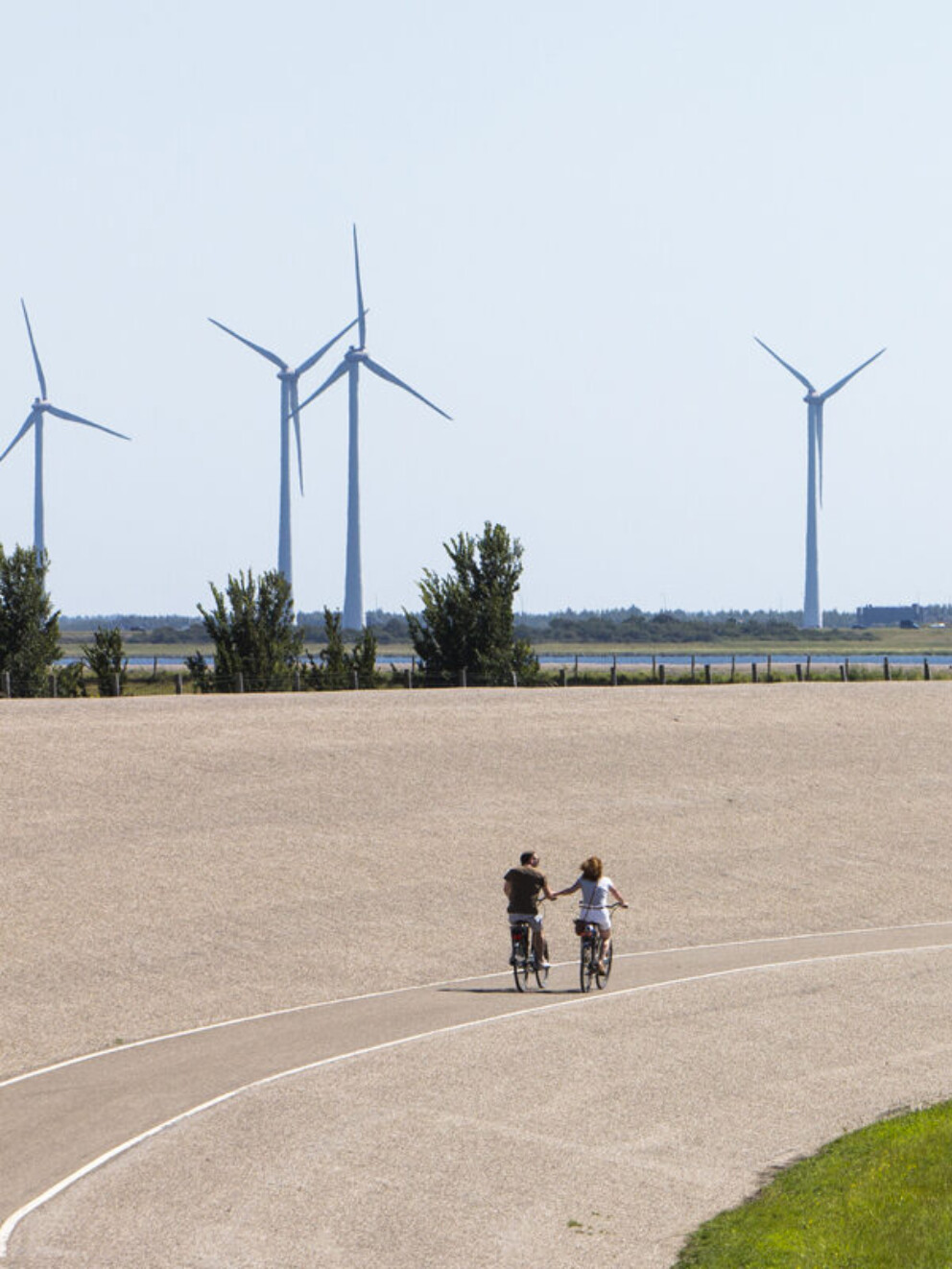 Windmolens en een zeedijk waar fietsers fietsen