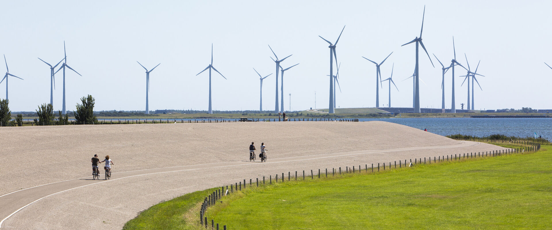 Windmolens en een zeedijk waar fietsers fietsen