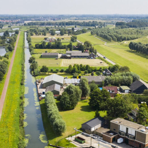 Luchtfoto van een rivier met dijk en ernaast een lager gelegen polder