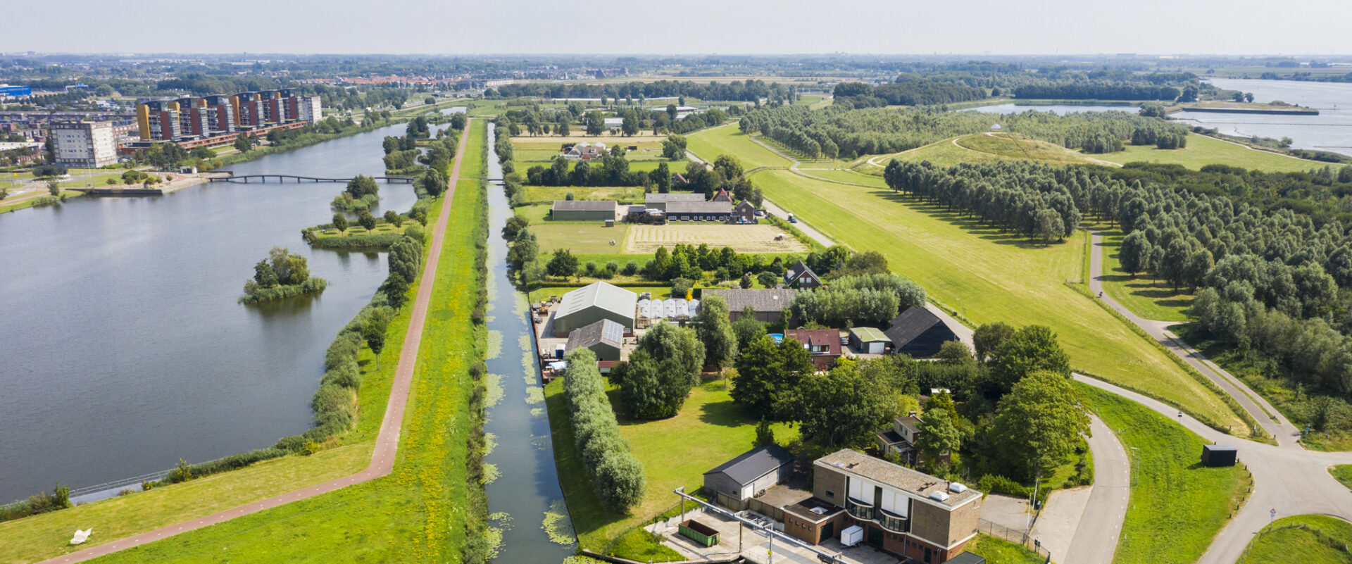 Luchtfoto van een rivier met dijk en ernaast een lager gelegen polder