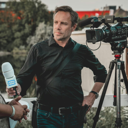 Nieuws report van de Unie van Waterschappen met een microfoon in de hand en naast zich een camera.